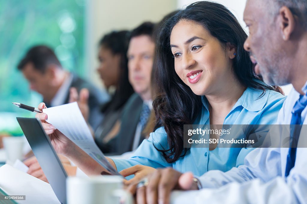 Young Hispanic businesswoman reviewing financial information during conference