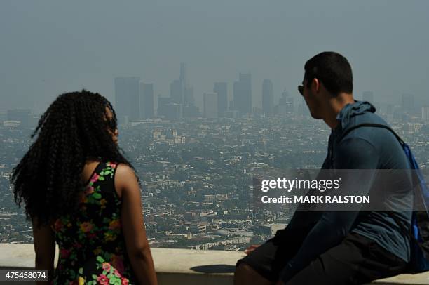 Tourists at the Griffith Observatory observation deck look out at the Los Angeles city skyline as heavy smog shrouds the city in California on May...