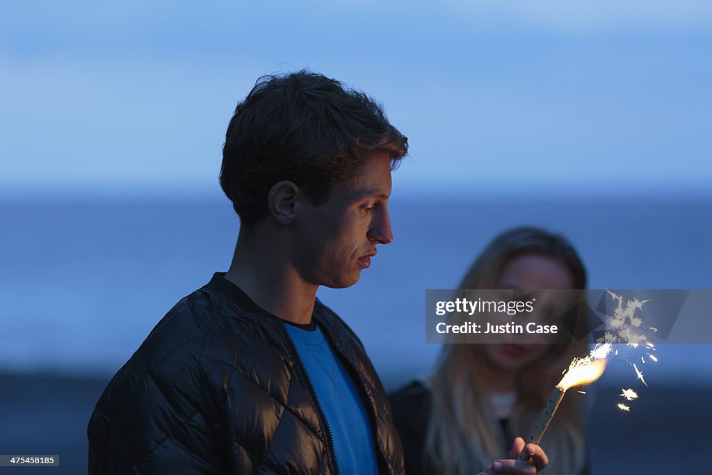 Boy and girl holding a burning firework at night
