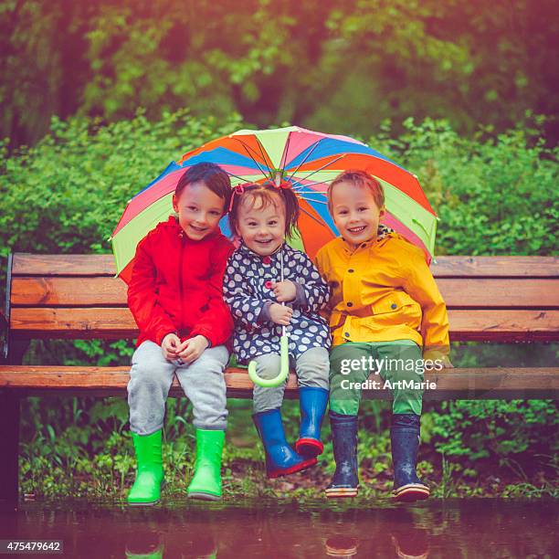 chilren under umbrella - baby boot stock pictures, royalty-free photos & images