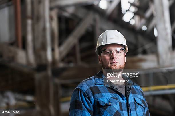 man wearing hardhat, safety goggles and plaid shirt - hard hat worker stock pictures, royalty-free photos & images