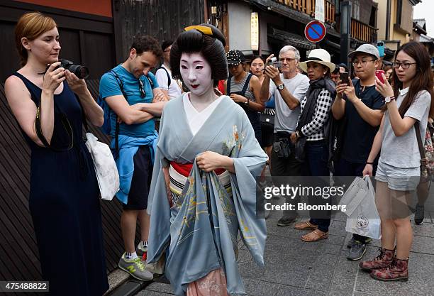 Tourists take photographs of a geiko walking through the Gion area of Kyoto, Japan, on Thursday, May 28, 2015. Spending by visitors to Japan jumped...