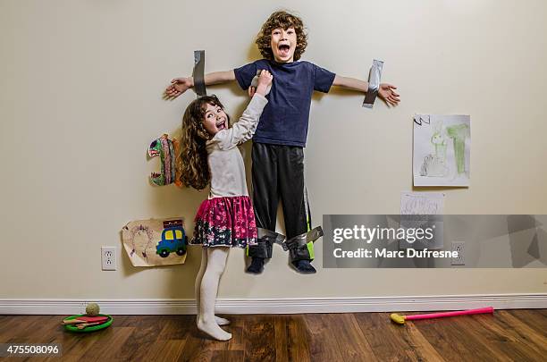 kid being duct taped on wall by his sister - kids mess stockfoto's en -beelden