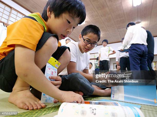 Children receive stationery as they were forced to evacuate as Mount Shindake of Kuchinoerabu Island erupted, at an evacuation center on May 30, 2015...