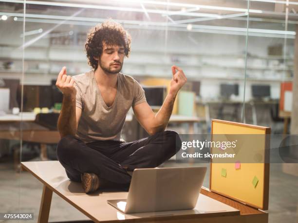 creative young man meditating in the office. - office zen stock pictures, royalty-free photos & images