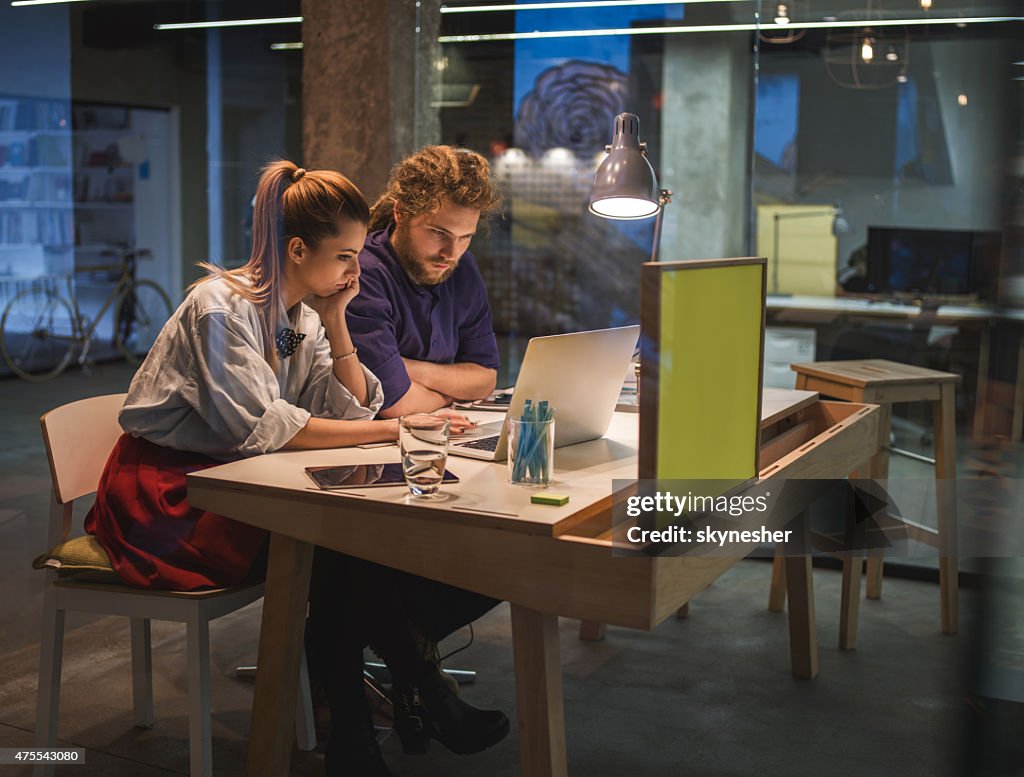 Young colegas su colaboración y usando la computadora portátil juntos en la oficina.