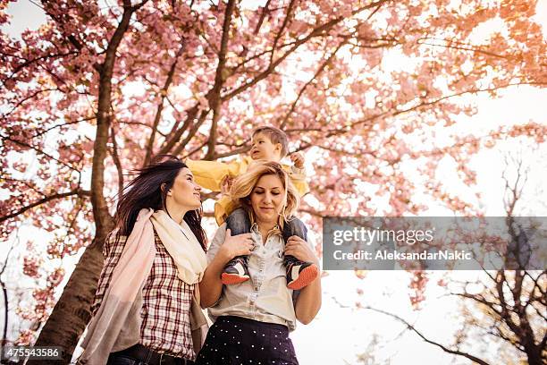 piggyback ride under the cherry blossom tree - lesbian stockfoto's en -beelden