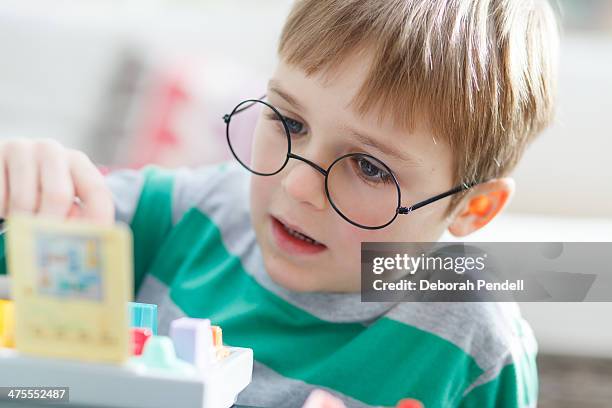 young boy wearing glasses playing with a puzzle - mormorsglasögon bildbanksfoton och bilder