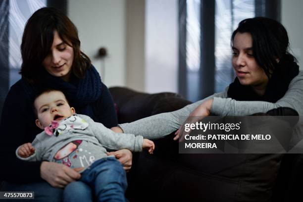 Same sex couple Olga and Matilde sit with their daughter Carolina at their home in Odivelas, on the outskirts of Lisbon on February 21, 2014. Matilde...