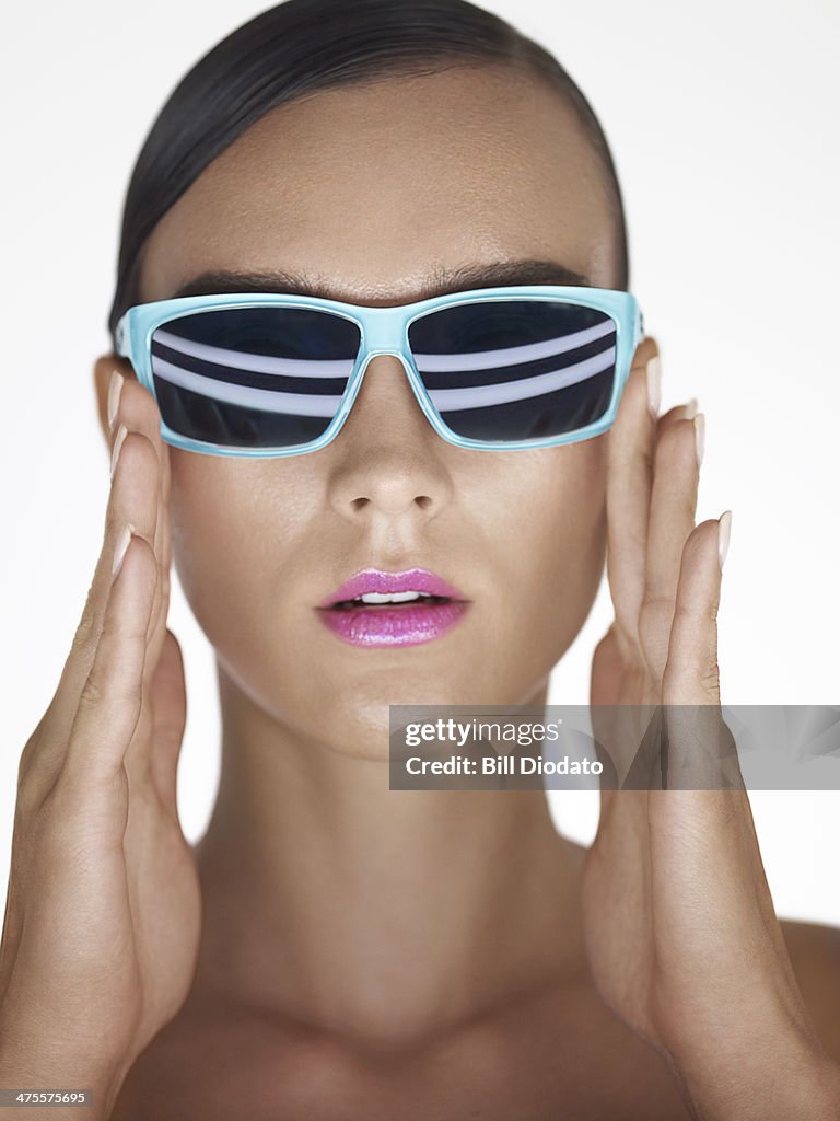 Woman holding sunglasses in studio