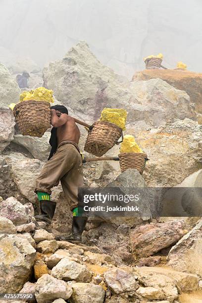 asian worker carrying baskets of sulfur in ijen volcano - slave holder stock pictures, royalty-free photos & images