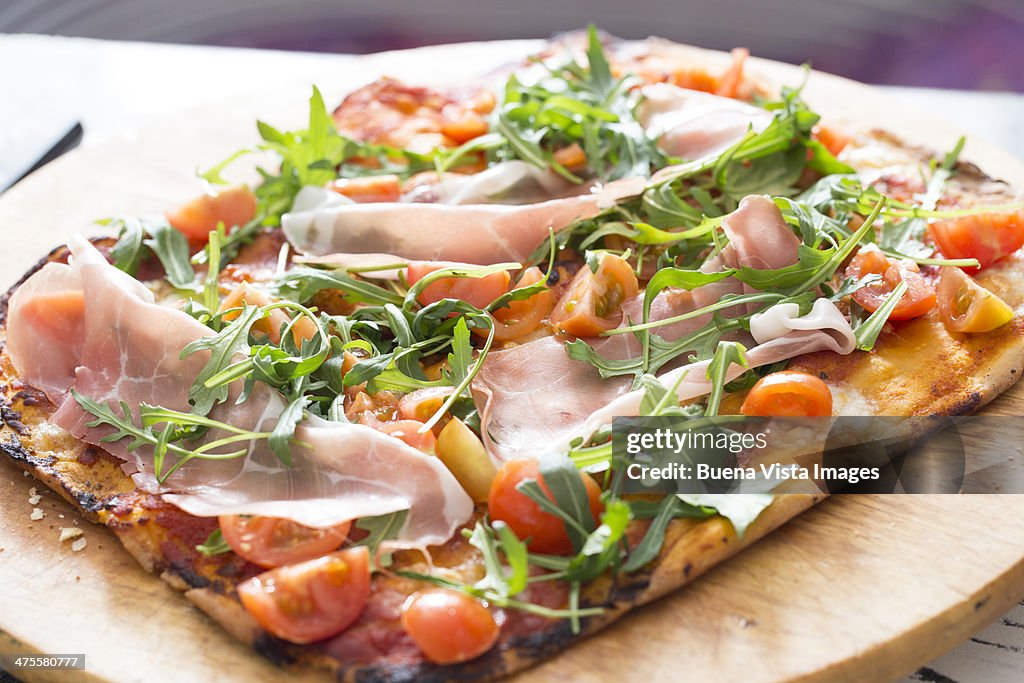 Pizza with ham and arugula (Eruca sativa)