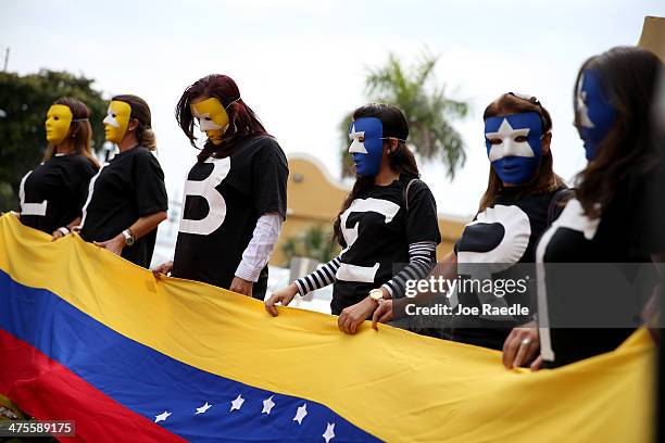 Supporters of the Venezuela opposition hold a flag and wear masks as U.S. Senator Marco Rubio and Florida Governor Rick Scott visit El Arepazo 2...