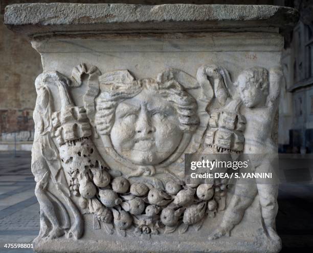 Naked genius holding up a garland and a large gorgoneion in the centre, relief from a Roman sarcophagus, Monumental Cemetery of Pisa, Tuscany, Italy....
