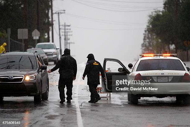 Roadblock keeps people from entering an evacuated neighborhood below the Colby Fire burn area as a storm brings rain in the midst of record drought...