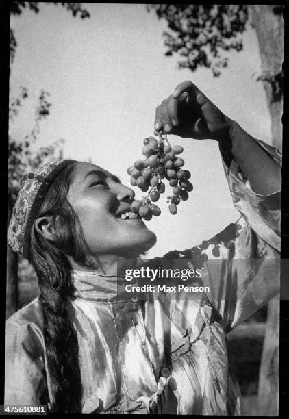Girl with a bunch of ripe grape, Uzbekistan, circa 1940.