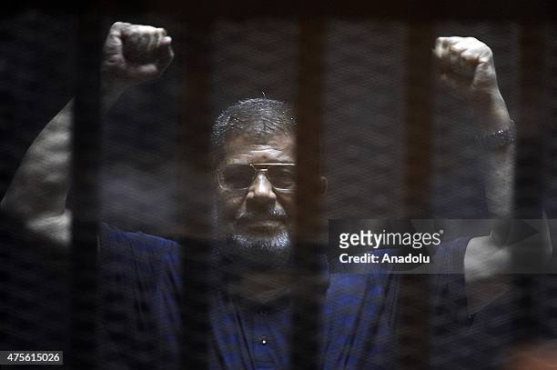 Former Egyptian President Mohamed Morsi gestures as he stands inside the defendants' cage in a courtroom during his trial in Cairo, Egypt, on June...