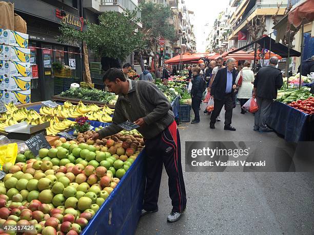 Vendor arranging stal with fresh fruits in the local open-air farmer's market in Kallidromiou street, downtown Athens.