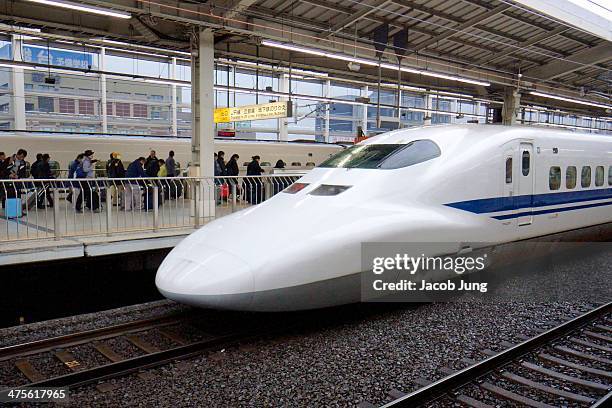 Series Shinkansen bullet train leaving Kyoto Station with passengers in the background.