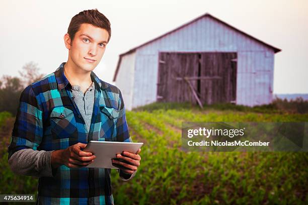 young farmer exterior portrait at sunset near barn with tablet - eastern townships quebec stock pictures, royalty-free photos & images
