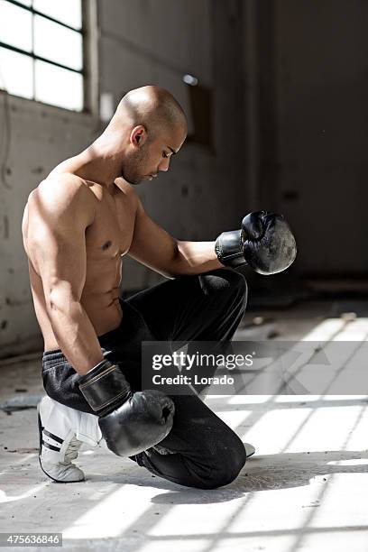 kneeling black man wearing boxing gloves - kneeling stock pictures, royalty-free photos & images