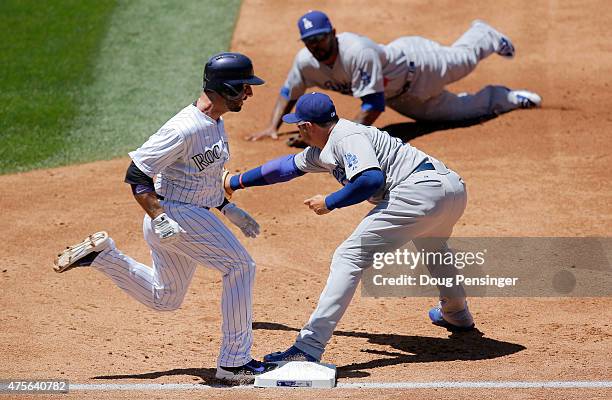 Daniel Descalso of the Colorado Rockies is safe at first with an RBI single as second baseman Howie Kendrick of the Los Angeles Dodgers makes the...
