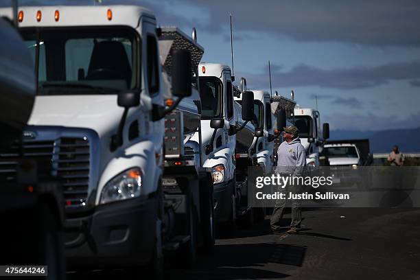 California Department of Fish and Game workers stand next to tanker trucks that are holding thousands of fingerling Chinook salmon that will be...