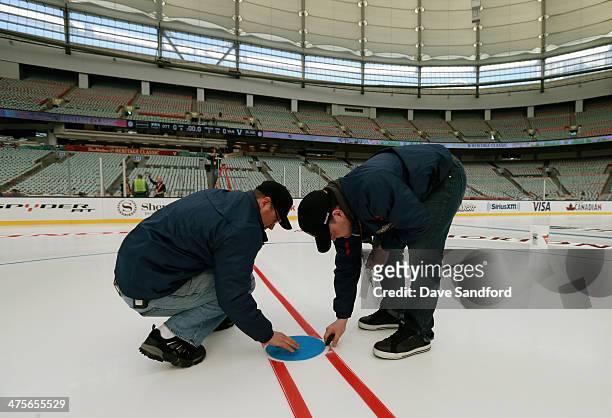 Ice crew members Mike Craig and Eric King mark center ice during the 2014 Tim Horton NHL Heritage Classic build out before the game between the...