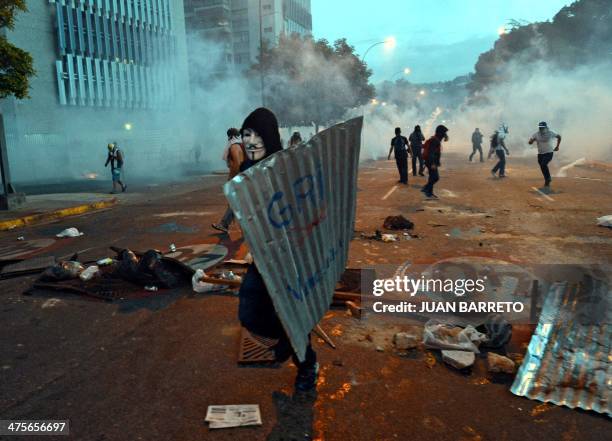 Demonstrator wears a Guy Fawkes mask as he holds a metal sheet during an anti-government protest in Caracas on February 28, 2014. Hundreds of people...