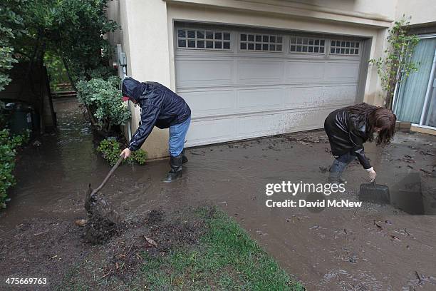 Lorenzo Tatone helps his neighbor Mari Poblete try to help control flooding at her home below the Colby Fire burn area as a storm brings rain in the...