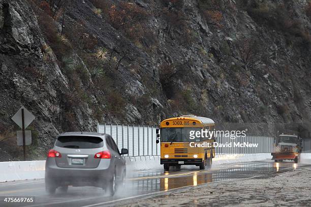 School bus passes below a charred hillside in the Colby Fire burn area as a storm brings rain in the midst of record drought on February 28, 2014...