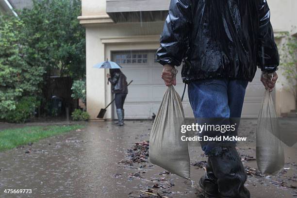 Lorenzo Tatone brings sandbags for this heighbor Mari Poblete to help control flooding at her home below the Colby Fire burn area as a storm brings...