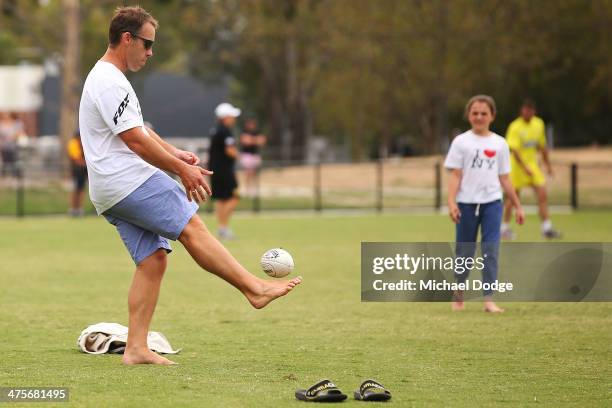 Hawthorn Hawks coach Alastair Clarkson kicks the ball with his kids at half time during the Werribee Tigers v Box Hill Hawks VFL practice match at...