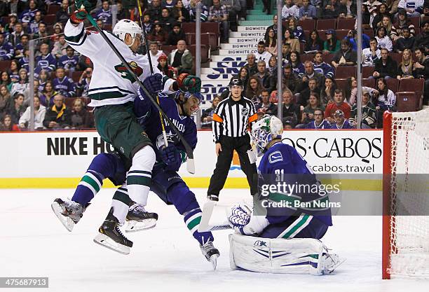 Nino Niederreiter of the Minnesota Wild collides with Chris Tanev of the Vancouver Canucks in front of goaltender Eddie Lack during the first period...