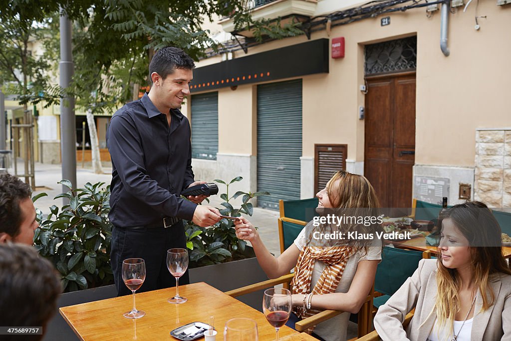 Waiter accepting creditcard from guest at cafe