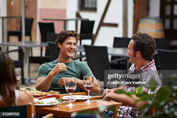 two guys lauging together at restaurant - pavement cafe stock pictures, royalty-free photos & images