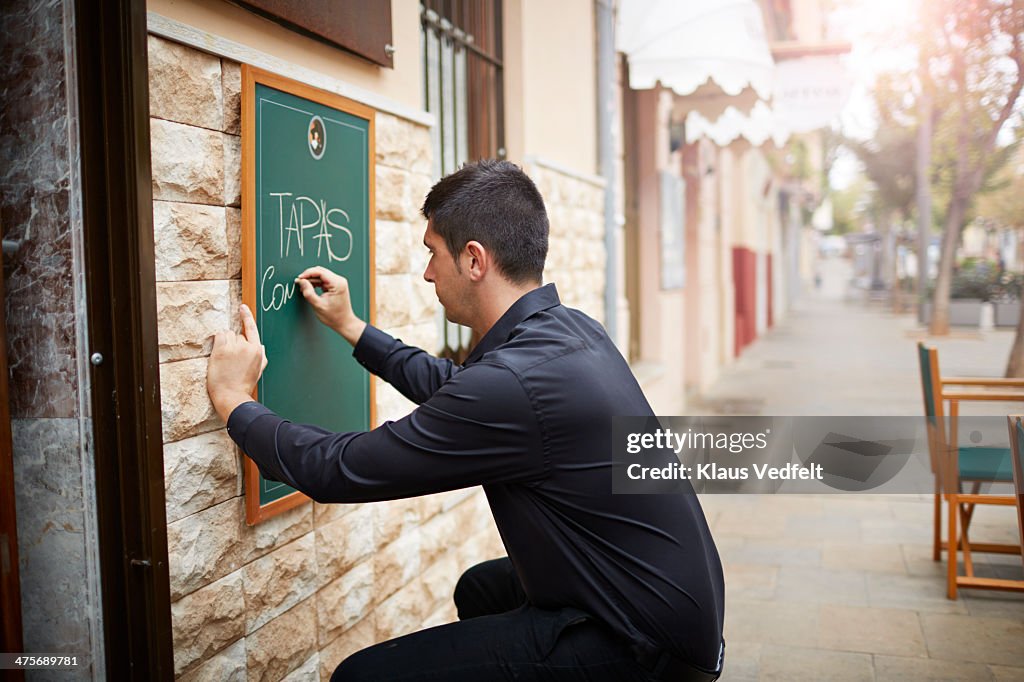 Restaurant owner writing tapas dishes on sign