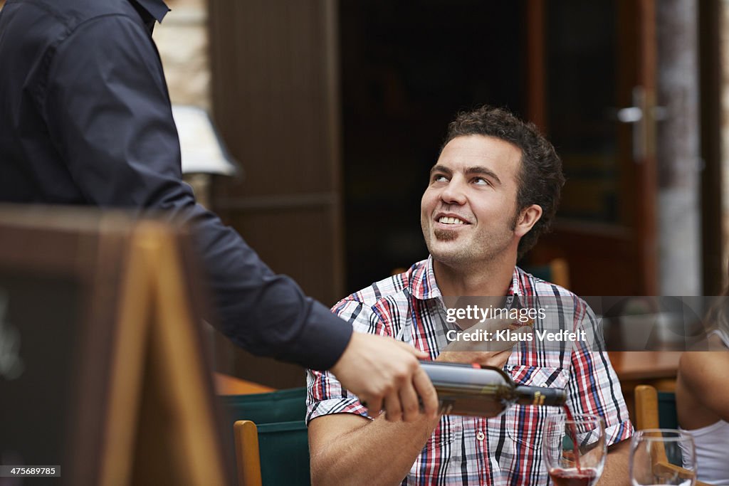 Waiter pouring redwine for male guest