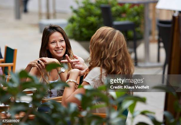 two women talking together at restaurant - straßencafe stock-fotos und bilder