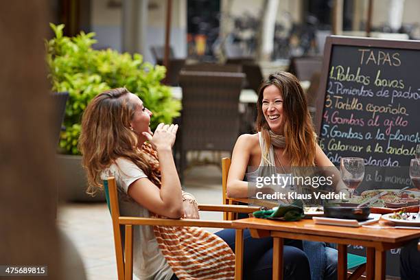 two girls laughing together at restaurant - terraza de cafetería fotografías e imágenes de stock
