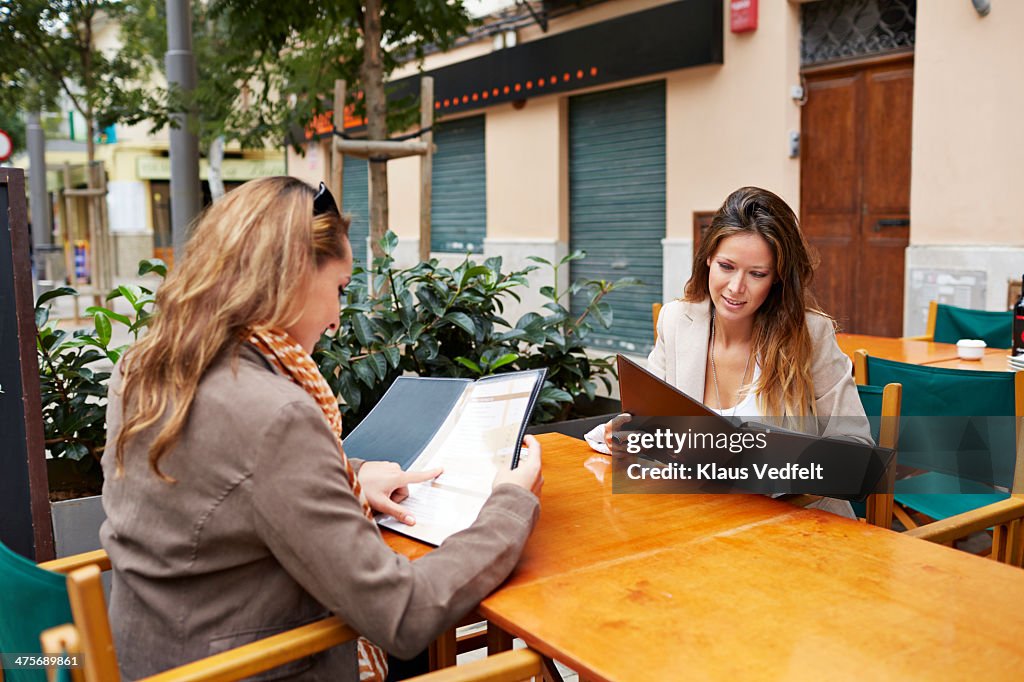 Two girlfriends looking at the menu at café