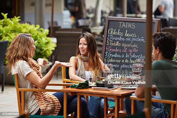 woman explaining to friends at restaurant - cafeterias en la calle fotografías e imágenes de stock