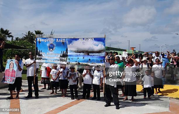 Islanders from nuclear weapons test-damaged Rongelap Atoll march while holding banners marking the 60th anniversary of the Bravo hydrogen bomb test...