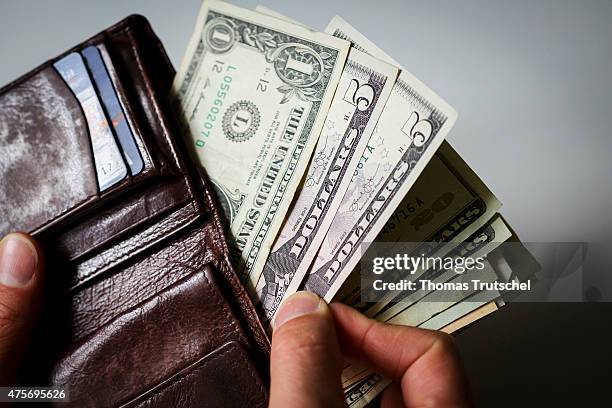 Man hold a wallet, filled with Dollar bills on June 03 in Berlin, Germany.