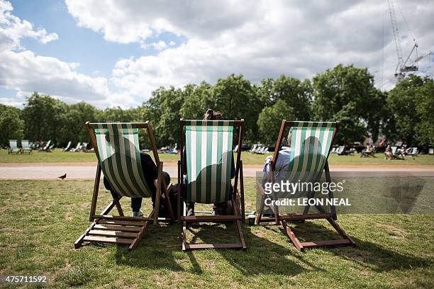 People sit in deckchairs as they enjoy the sun in Green Park, central London on June 3, 2015. AFP PHOTO/Leon Neal