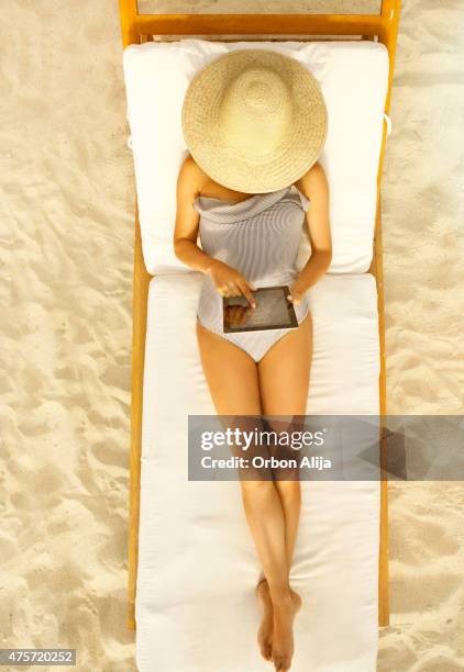 donna con tablet in spiaggia - sedia a sdraio foto e immagini stock