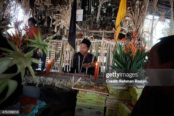 Guy from Mah Meri tribe who wears Malay traditional costume, "Baju Melayu" lits joss sticks during Ari Muyang festival celebration on March 1, 2014...