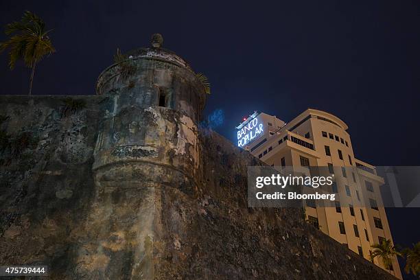 Signage is illuminated on the Banco Popular building, near the wall that surrounds Old San Juan, Puerto Rico, on Friday May 29, 2015. For the hedge...