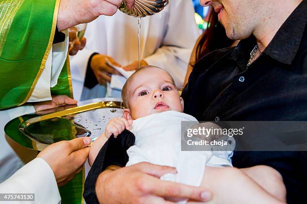 sacerdote es baptizing little baby en una iglesia. - bautizo fotografías e imágenes de stock