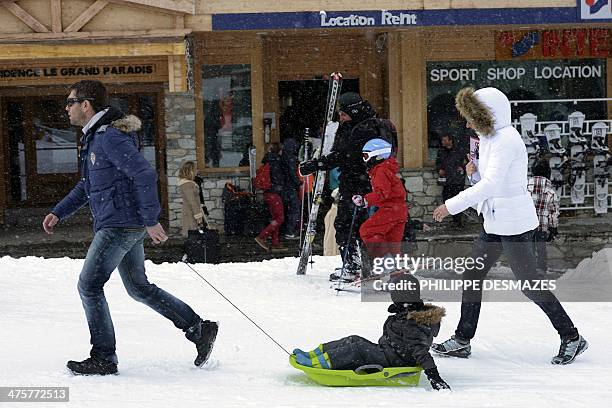 Man pulls his son in a sled as he walks with his wife at the French Alps Val d'Isere ski resort, on March 1, 2014 during France's school holydays....